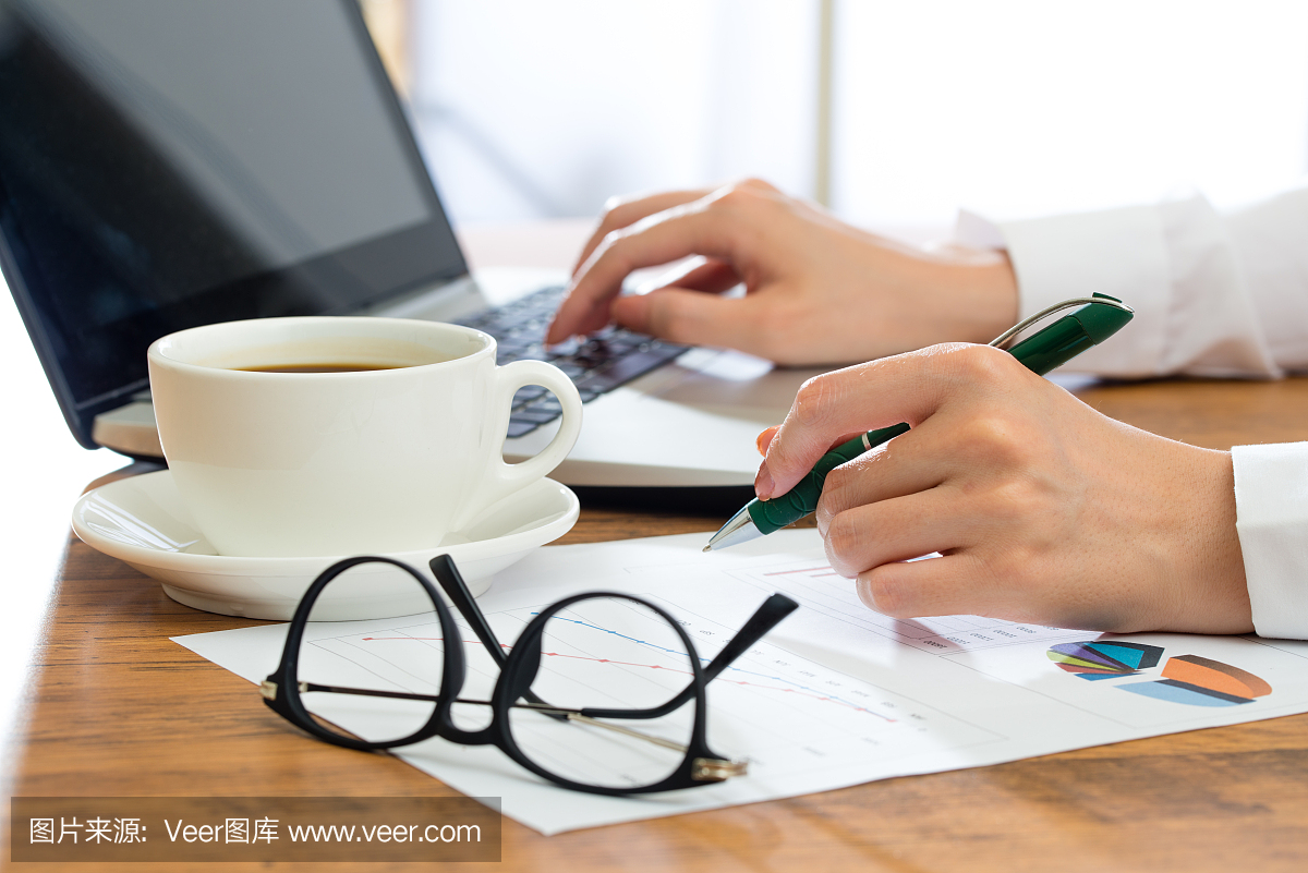 女商人使用筆記本電腦,在辦公桌上寫作